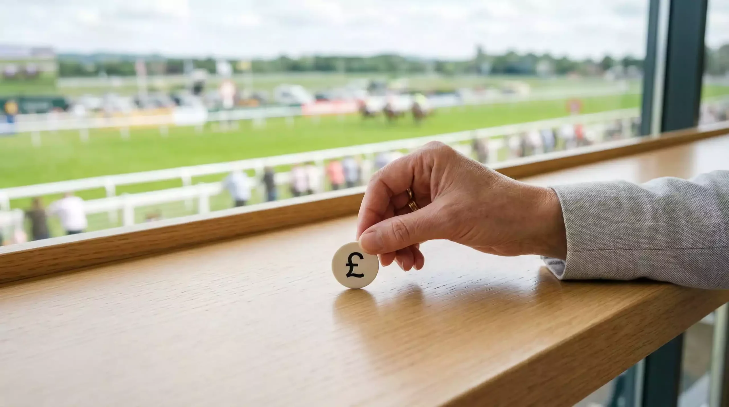 Hand placing a small £5 chip on a simple betting counter at a racecourse